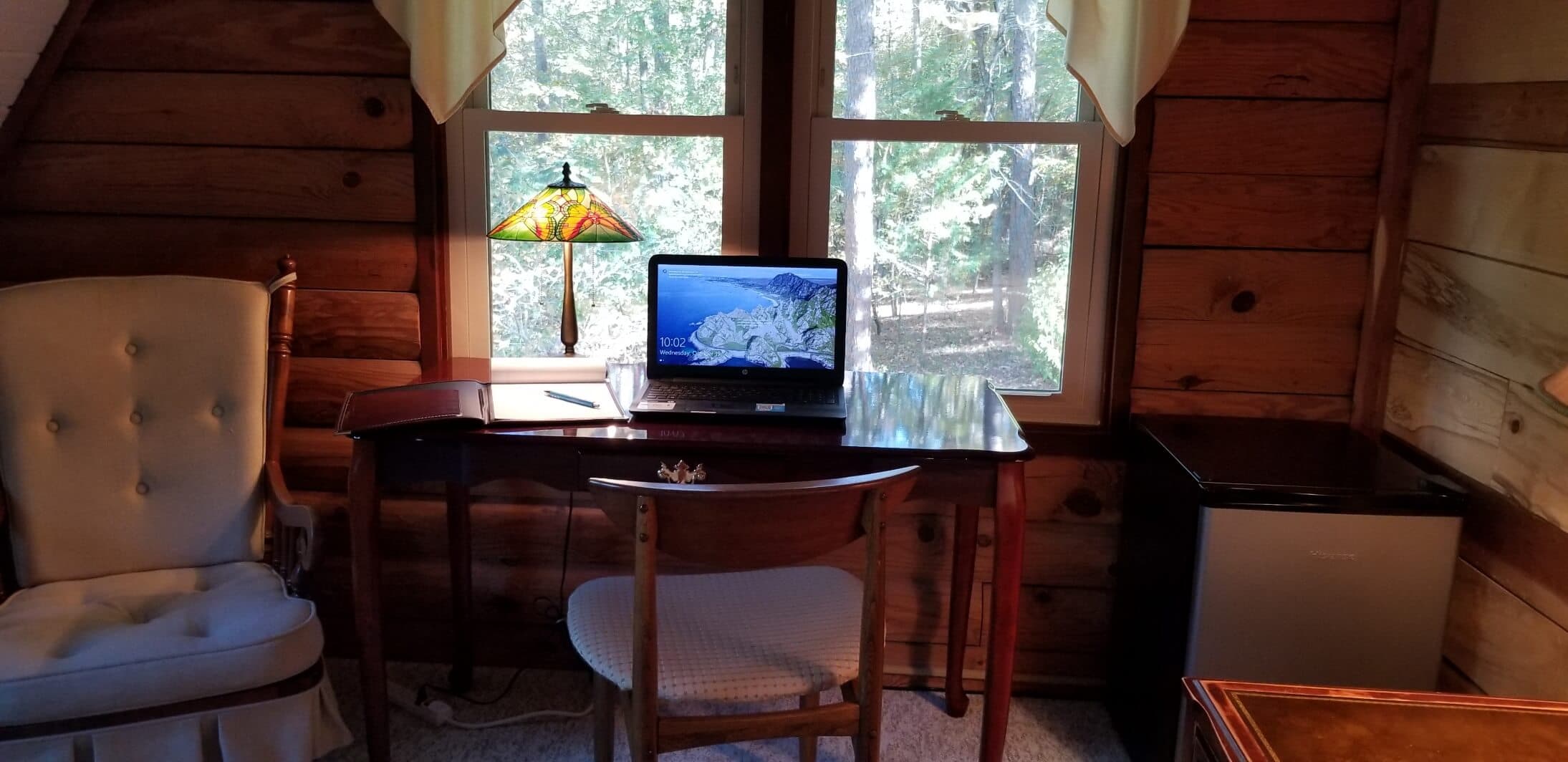 Cozy cherry wood writing desk set up with a laptop and notebook in front of woodland view windows at Tiffany's Bed and Breakfast near Hot Springs, AR Cozy cherry wood writing desk set up with a laptop and notebook in front of woodland view windows at Tiffany's Bed and Breakfast near Hot Springs, AR