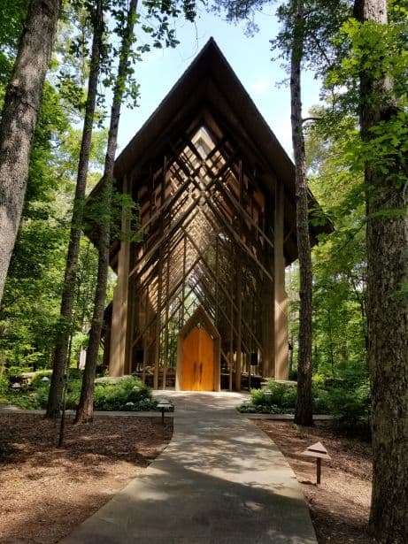 The exterior of Anthony Chapel at Garvan Woodland Gardens, featuring intricate wood beams and a stone path leading to the wooden entrance doors