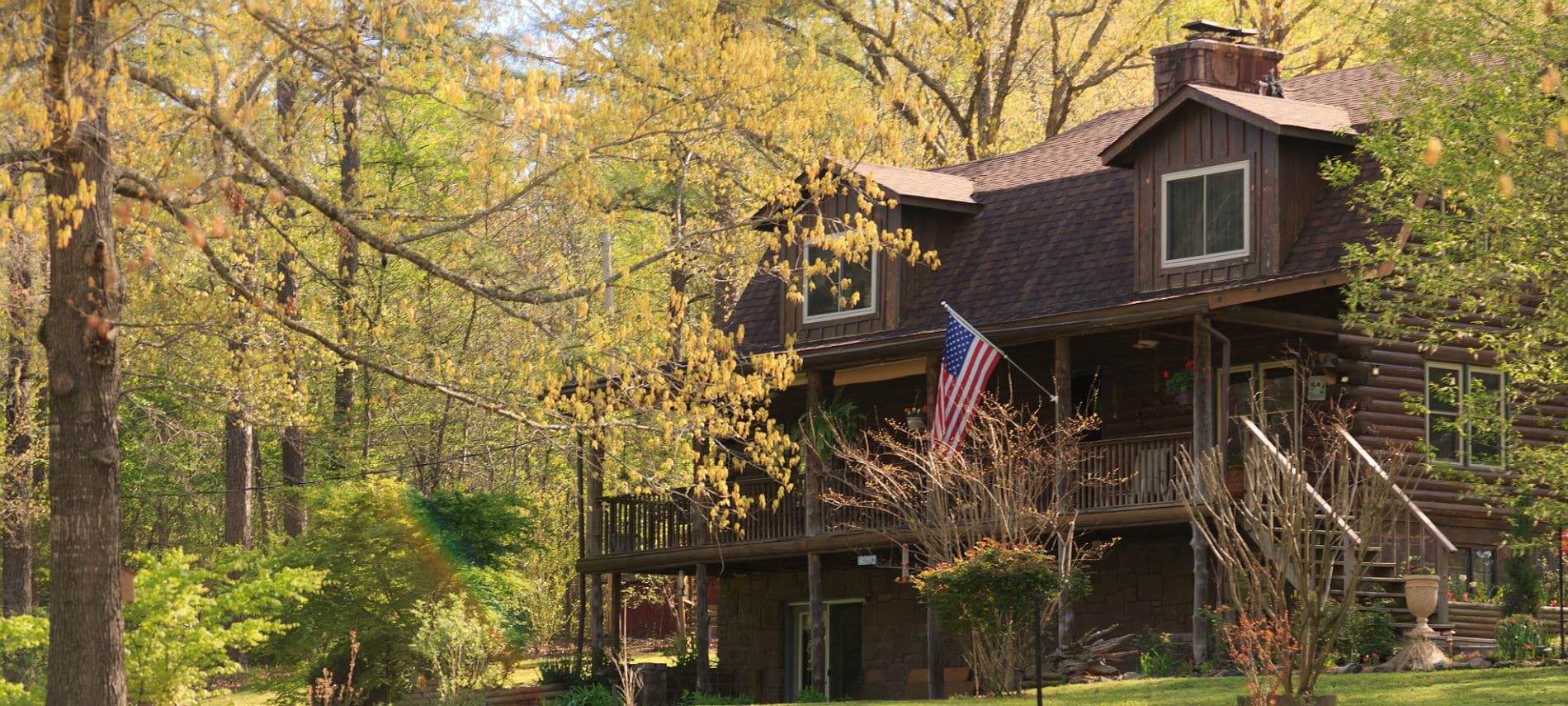 Exterior of the inn with a large front porch, log siding and an American flag hanging from the front post.