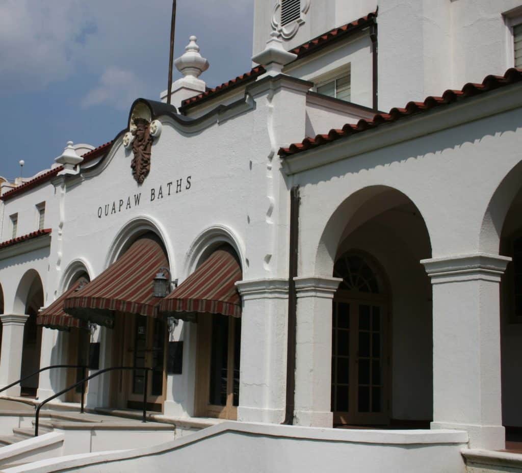 A Spanish Colonial Revival style building with white stucco walls and a series of arches on the front, names the Quapaw Bathhouse